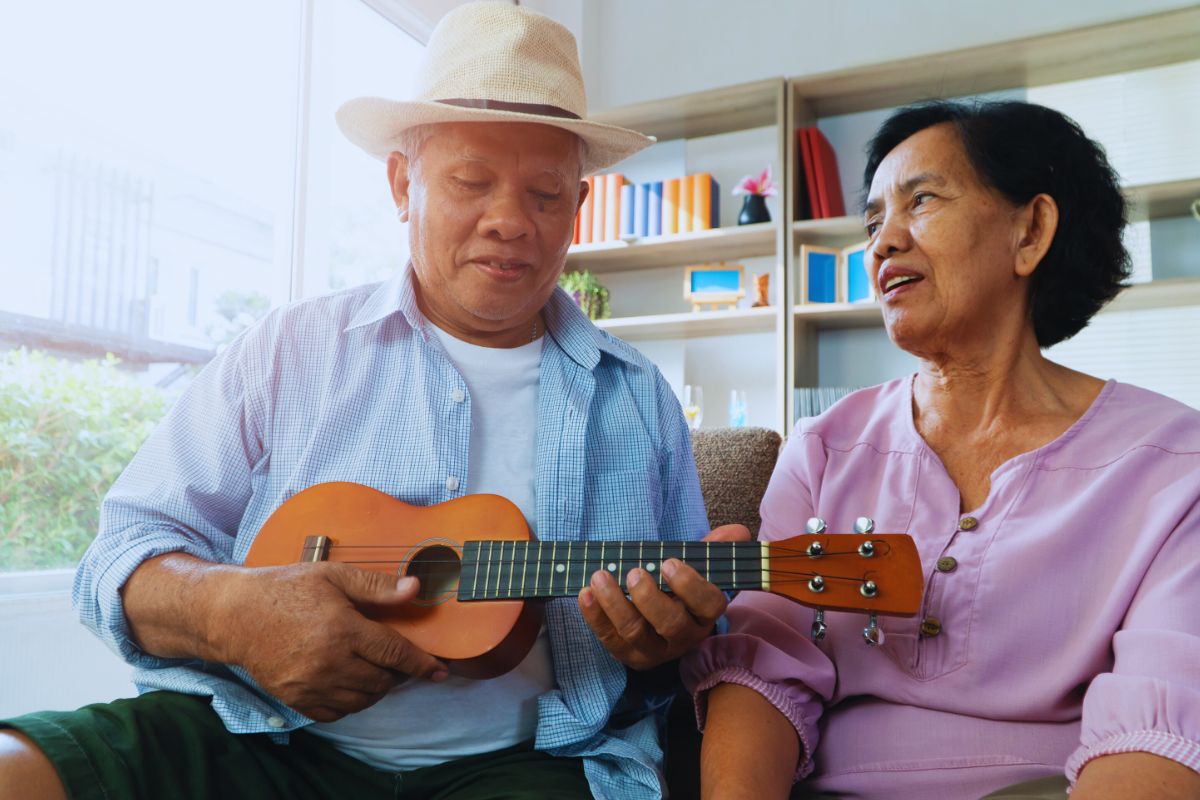 Older adult smiling at home while talking with family, representing safe and independent aging in Hawaii. Older adult at home with family, representing senior safety in Hawaii